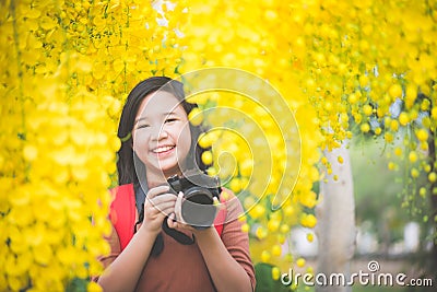 Asian girl take photo with blooming yellow flower Stock Photo