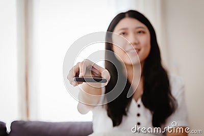 Asian girl teen hand holding pointing remote control to watching television at home Stock Photo