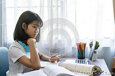 Asian girl thinking hard studying homework online lesson at home Stock Photo