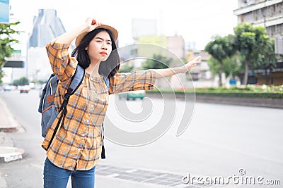 Asian girl tourists Standing on the roadside To wave a taxi for travel in the capital Stock Photo