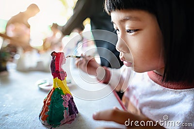 An Asian girl is painting plaster dolls with colored posters. Stock Photo