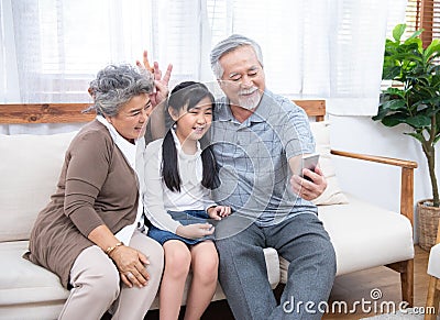 Asian Grandfather taking selfie with couple Grandparent and granddaughter with happy feeling by mobile phone in house, Long live Stock Photo