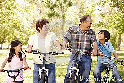 Asian grandparents and grandchildren riding bikes in park Stock Photo