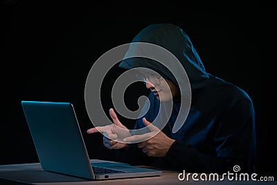 Asian hacker hacking computer network with laptop in dark. Cyber security concept Stock Photo