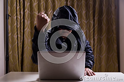 Asian hacker show fist while hacking computer network Stock Photo