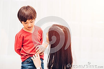 Asian happy beautiful mother getting dressed clothes on her kids Stock Photo