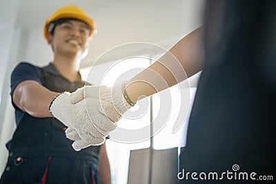 Asian Happy Craftsman or Carpenter worker male wear work safety helmet, smiling and greeting by handshake with Joiner builder Stock Photo