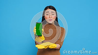 Asian homemaker holding chroma key mock up mobile phone with greenscreen display Stock Photo