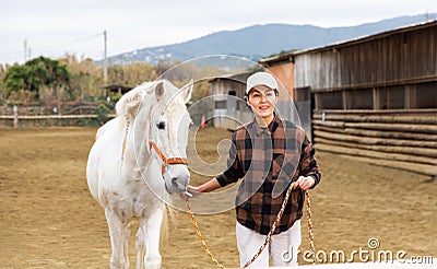 Asian horsewoman training white horse in outdoor riding arena Stock Photo