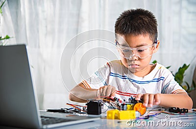 Asian kid boy assembling the Arduino robot car homework project at home Stock Photo