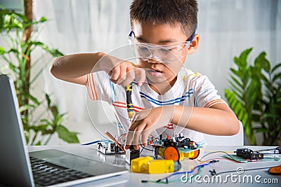 Asian kid boy assembling the Arduino robot car homework project at home Stock Photo