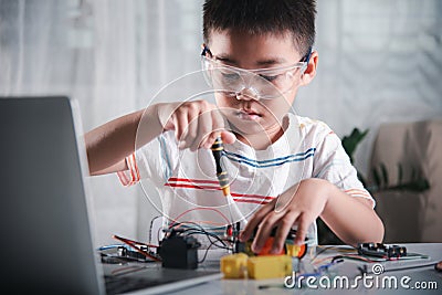 Asian kid boy assembling the Arduino robot car homework project at home Stock Photo