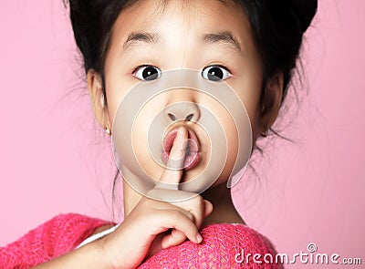 Asian kid girl in pink sweater shows shhh quiet sign on pink Stock Photo
