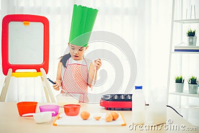 Asian kid having fun with cooking and preparing the dough, bake cookies in the kitchen Stock Photo