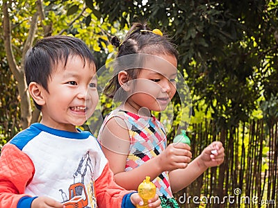 Asian kids boy and girl playing bubbles together outdoor in nature countryside garden background. Stock Photo