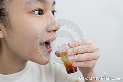 Asian lady girl rinsing the mouth or gargling with medicine of medical disinfectant,protect against the Coronavirus COVID-19 in Stock Photo