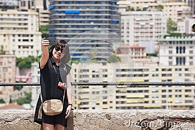 Asian lady makes selfie with a smartphone at the viewpoint in Monaco. Editorial Stock Photo