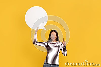 Asian lady smiles gladfully points up, shows white communication bubble Stock Photo