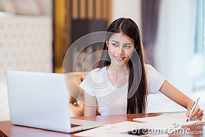 Asian lady student do home work on the desk with computer notebook Stock Photo