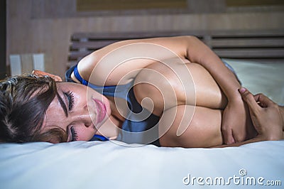 Asian latin mixed woman lying on bed suffering stomach cramp ache and period pain feeling sick and unwell in cycle and painful me Stock Photo