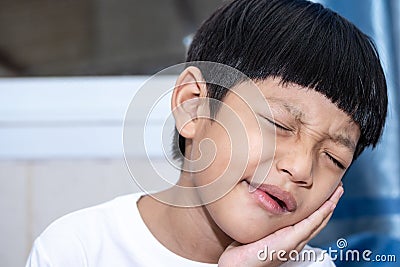Asian little boy is doing a terrible toothache. Portrait a little boy suffering from toothache. Oral Care Concepts Stock Photo