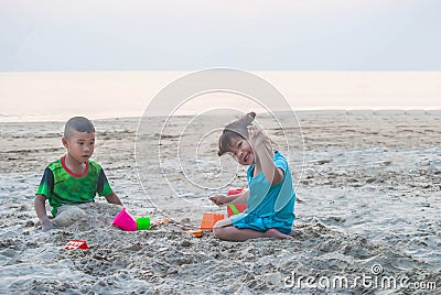 Asian little boy and girl are playing together on the sandy beach. Stock Photo