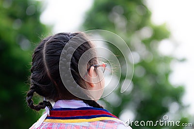 Asian little child girl with black hair braid turned her back to the camera. Children wear school uniforms and wear glasses. Stock Photo