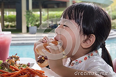 Asian Little Chinese Girl Eating Burger and French fries Stock Photo