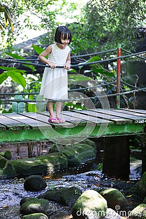 Asian Little Chinese Girl standing on the wooden bridge Stock Photo