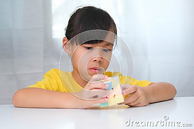 Asian little cute girl holding Rubik's cube in her hands and playing with it. Editorial Stock Photo