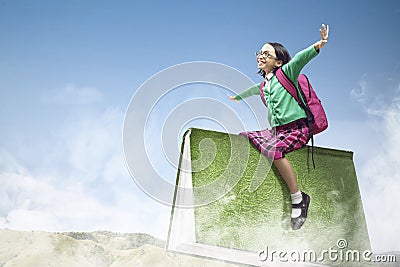 Asian little girl with a backpack flying on the book to back to the school Stock Photo