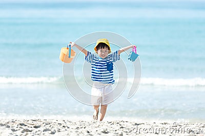 Asian little girl have fun and play yellow ball on the beach. Family kid tourism travel enjoy and freedom in summer and holiday f Stock Photo