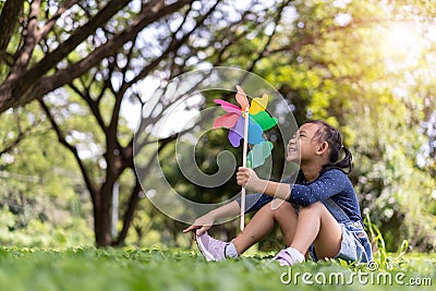 Asian little girl playing with paper windmill in the garden Stock Photo