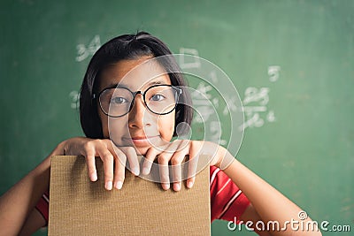 Asian little girl smiles and holds a book in her hand and is using her thoughts in the classroom, Education lifestyle concept Stock Photo