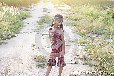 Asian little girl wore a dress made of Thai loincloth or Kamar band or Commer band standing and smile bright in the fields. Stock Photo