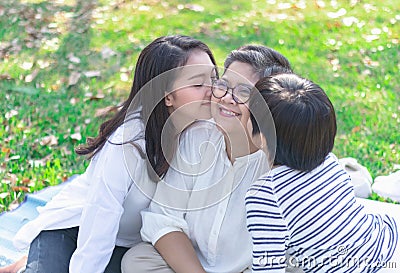 Asian lovely young daughter and grandson kiss happy and healthly senior woman or pleasure grandmother in moment of beautiful love Stock Photo