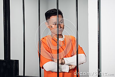 Asian mafia gang member is serving time behind bars. Sad portrait in a prison cell. Stock Photo