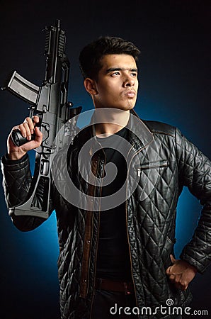 Asian mafia guy in black jacket and automatic rifle in hand Stock Photo