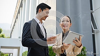 Asian male banker having a conversation with aged businesswoman outside the building Stock Photo