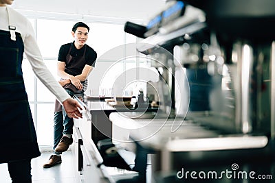 Asian male barista teacher sitting on the counter and waiting for the class ready. Coffee-making class for start-up entrepreneurs Stock Photo