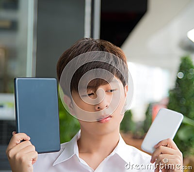 Asian male decide and hesitate to use smart devices Stock Photo