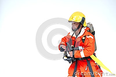 An Asian male firefighter in red protective uniform, mask and helmet with fire extinguisher standing on white backgrond. Stock Photo