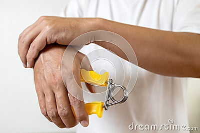 Asian male holding a spring hand grip for exercise,physical therapy or recovery,man patient doing hand finger and wrist exercise, Stock Photo