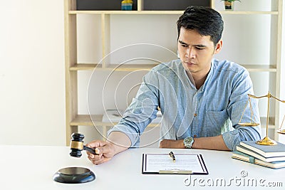 An Asian male lawyer works in an office with hammers and tiger skin scales on the table. Stock Photo