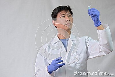 Asian Male scientist looking at small test tube Stock Photo