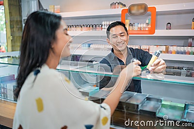 asian male shopkeeper showing the vape mod to the female customer Stock Photo