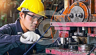 Asian male worker In industries that wear glasses, safety hats and safety uniforms Wrench tool holder stand Stock Photo