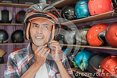 Asian man attaches the strap buckle while wearing the helmet Stock Photo