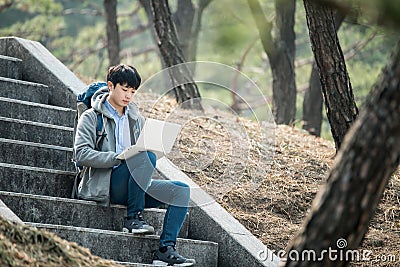 Asian man backpacking using laptop. Stock Photo