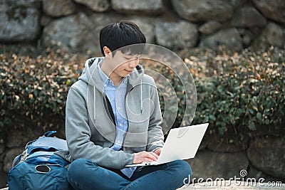 Asian man backpacking using laptop. Stock Photo